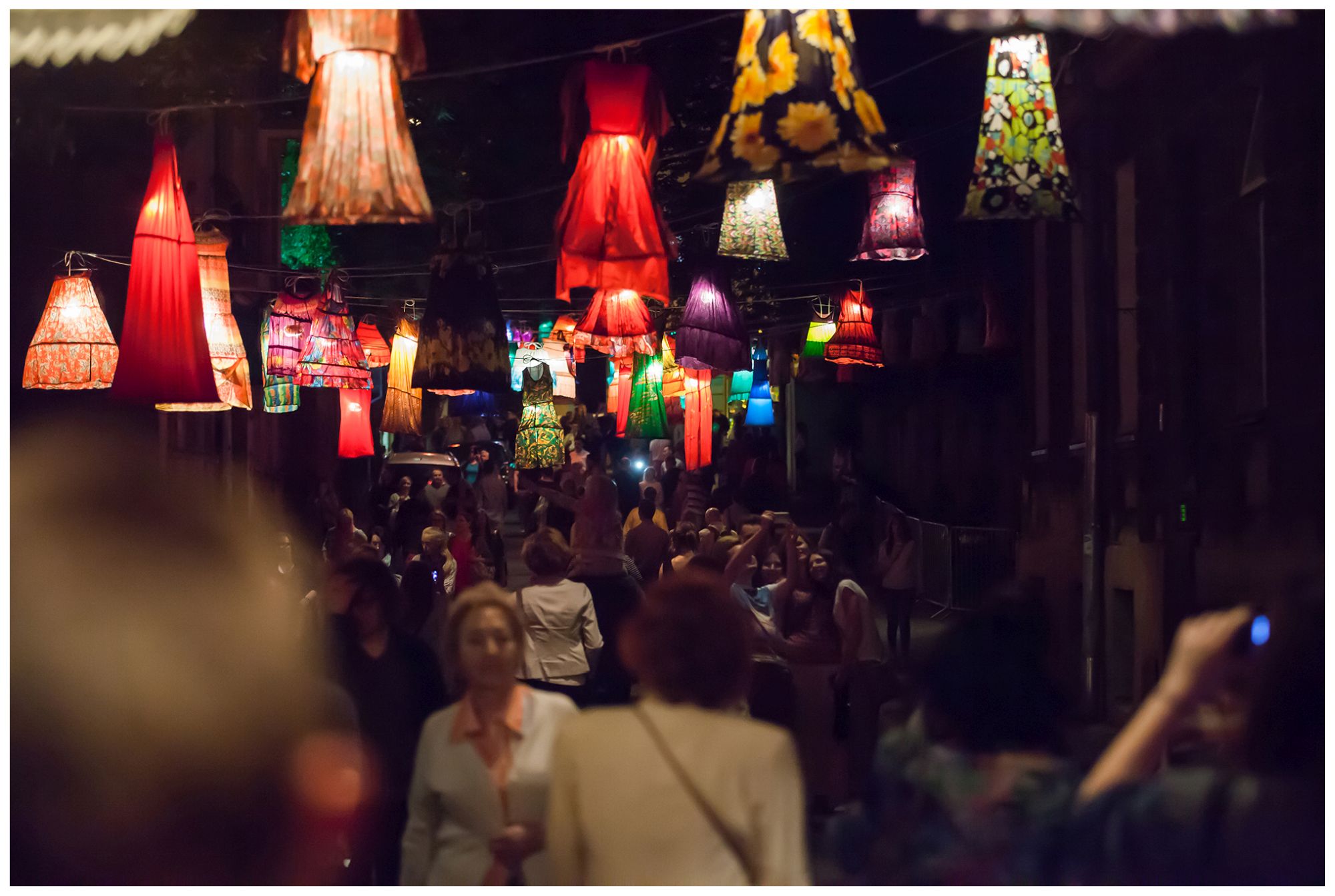 Instalacja na Nocy Kultury, Lampiony z kolorowych sukien zawieszone ponad ulicą. spacerujący tłum ludzi