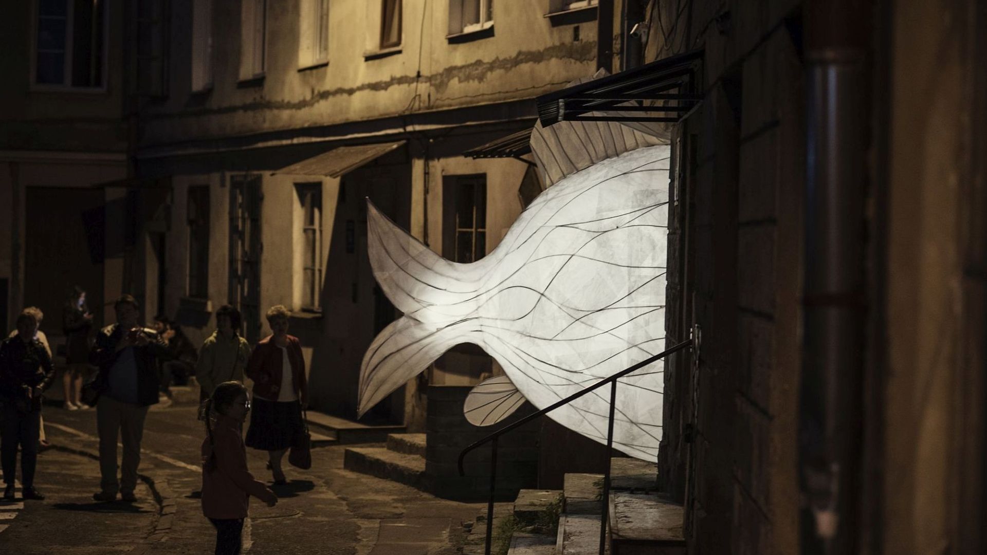 ul. Furmańska Instalacja dużej podświetlonej ryby, która wystaje z drzwi do kamienicy.