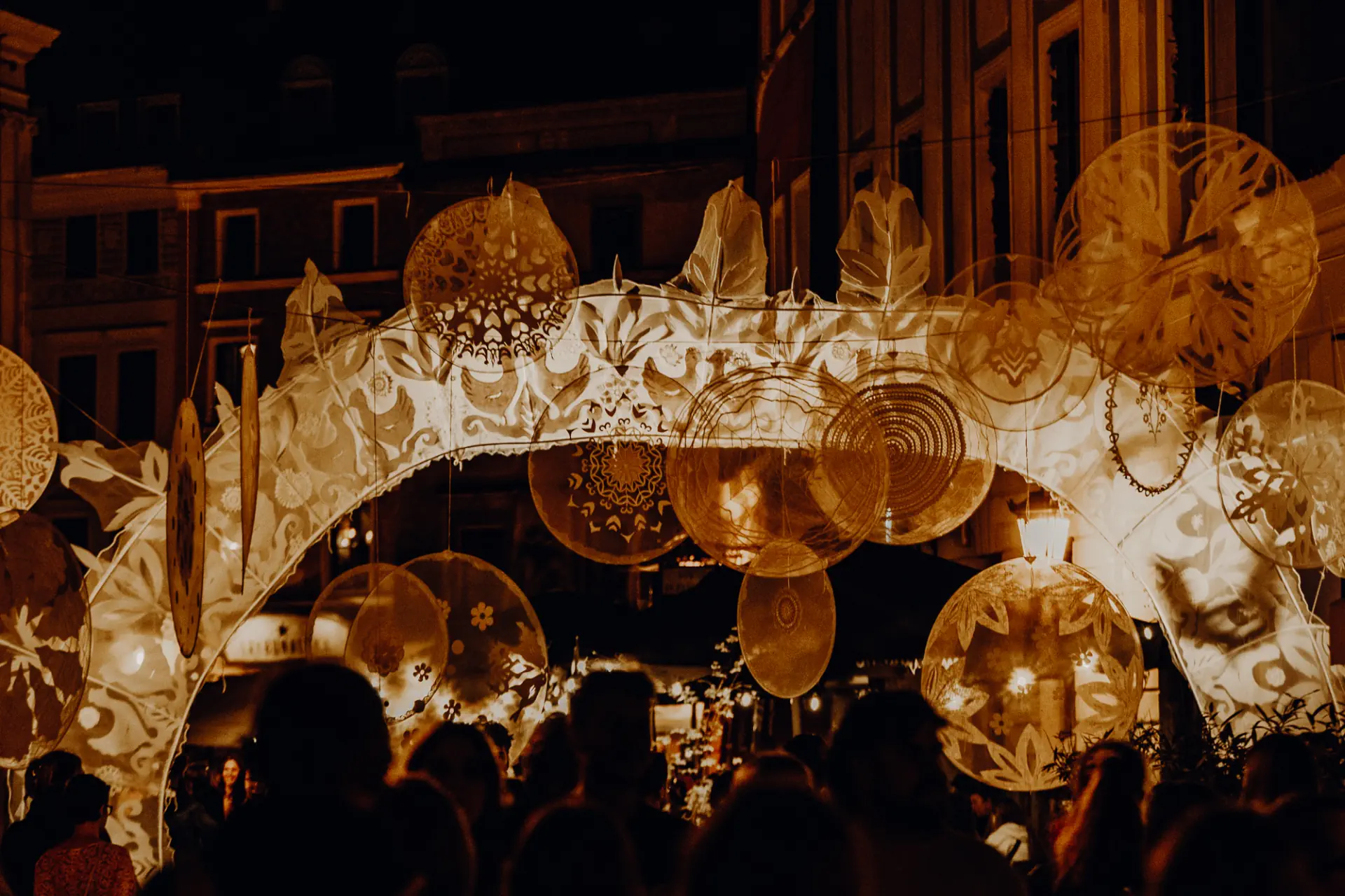 Instalacja artystyczna. Koła z firanek wiszą nad głowami przechodniów.